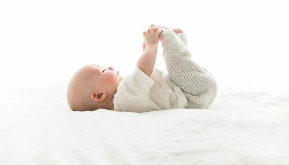 Newborn checkup babie on his back grabbing feet